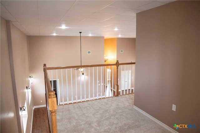 carpeted empty room with a drop ceiling, visible vents, and baseboards