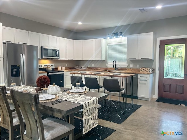 3306 Cypress, Victoria, TX 77901 - kitchen with appliances with stainless steel finishes, butcher block countertops, finished concrete flooring, white cabinetry, and recessed lighting