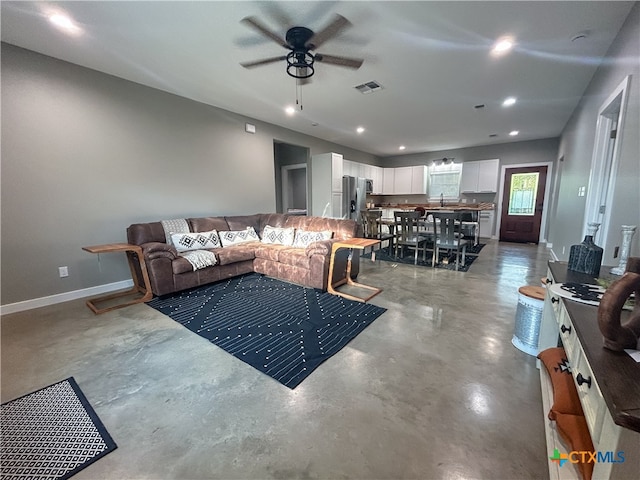 living room featuring concrete flooring, sink, and ceiling fan