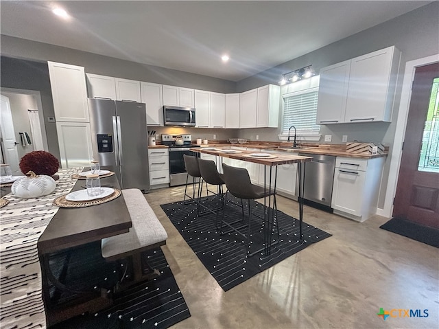 kitchen featuring wooden counters, white cabinetry, a healthy amount of sunlight, and appliances with stainless steel finishes