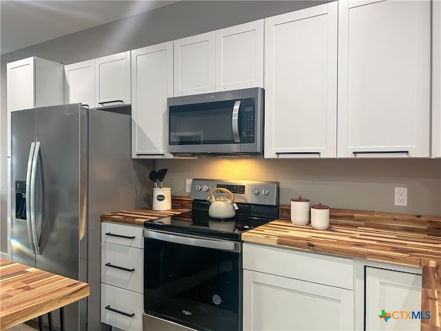 kitchen with wooden counters, white cabinetry, and appliances with stainless steel finishes