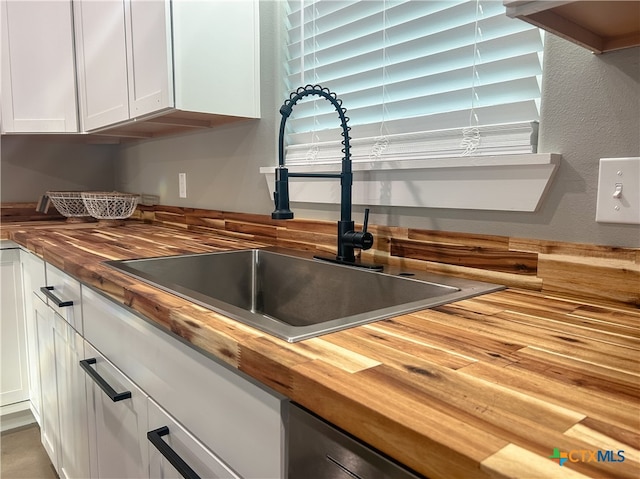 room details with white cabinetry, sink, and wood counters