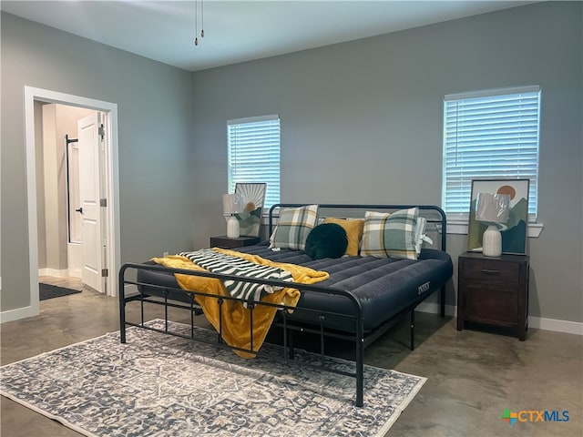 bedroom with connected bathroom and concrete floors