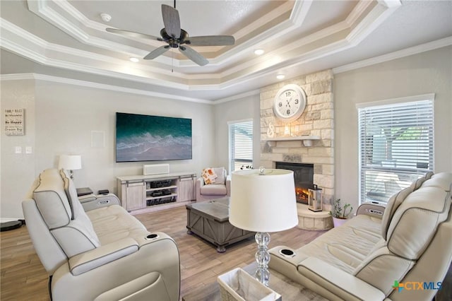5106 La Piedra Ln, Killeen, TX 76549 - living room featuring a raised ceiling, ornamental molding, light wood-style floors, a stone fireplace, and a ceiling fan