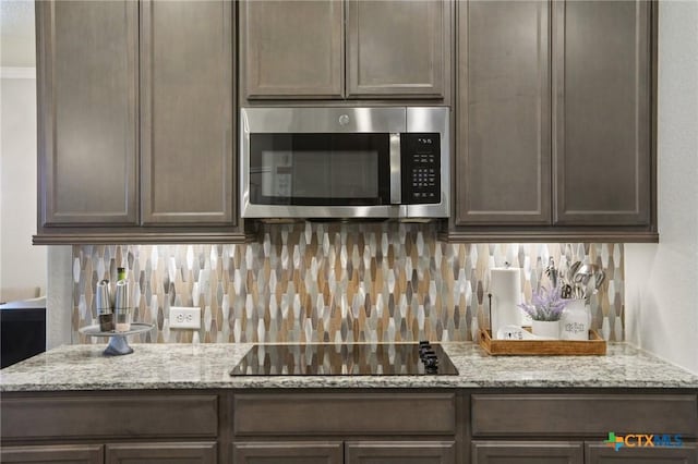 5106 La Piedra Ln, Killeen, TX 76549 - kitchen featuring stainless steel microwave, black electric stovetop, decorative backsplash, and dark brown cabinetry