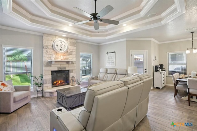 5106 La Piedra Ln, Killeen, TX 76549 - living room featuring a tray ceiling, ceiling fan, crown molding, light wood-style flooring, and a stone fireplace