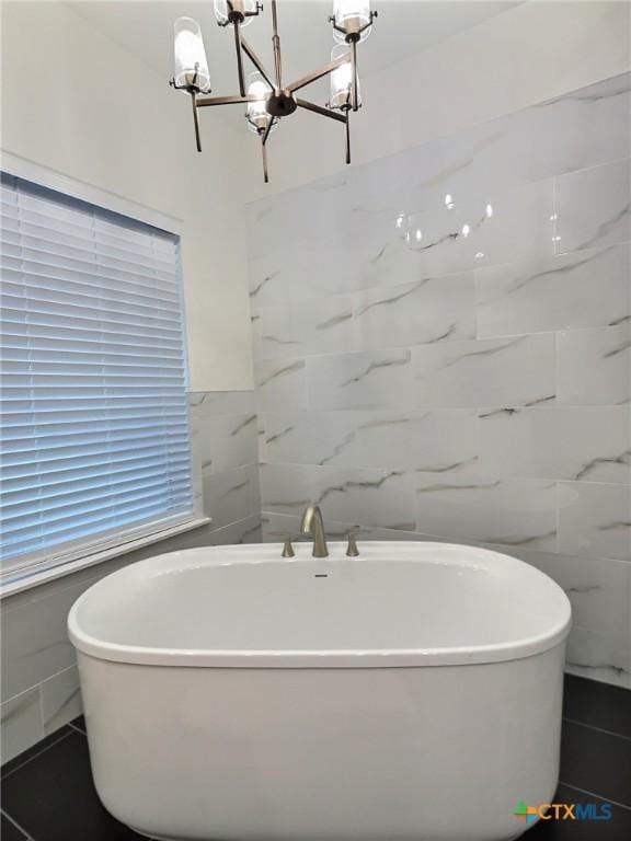 bathroom featuring a tub to relax in and an inviting chandelier