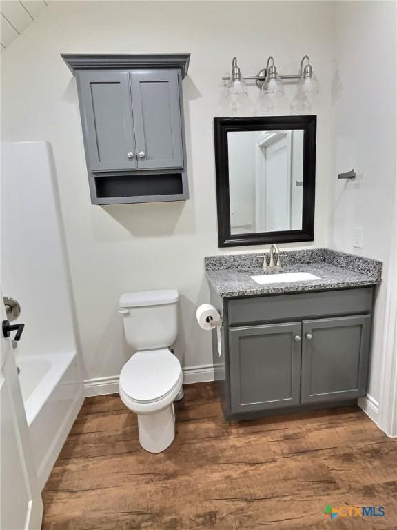 full bathroom featuring hardwood / wood-style flooring, vanity, toilet, and shower / tub combination