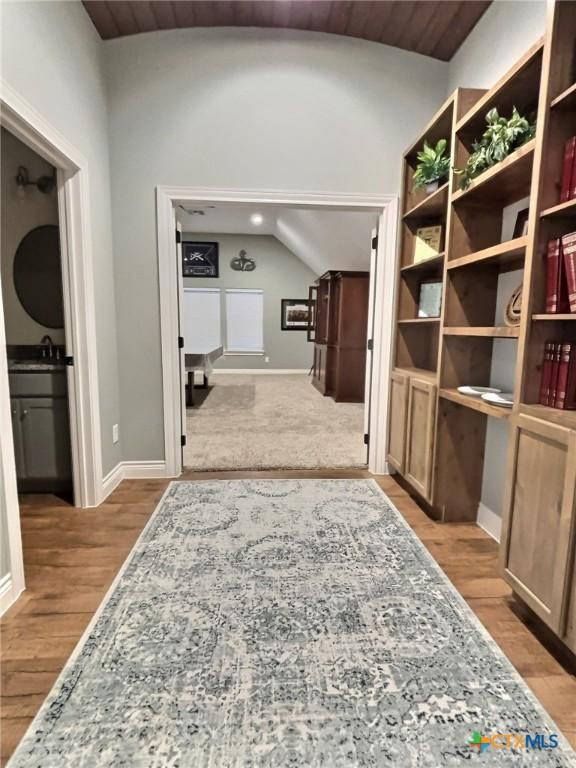 hallway featuring light hardwood / wood-style floors, lofted ceiling, sink, and wooden ceiling