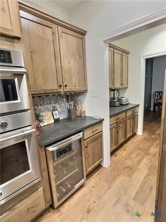 kitchen featuring decorative backsplash, stainless steel double oven, light hardwood / wood-style flooring, and beverage cooler