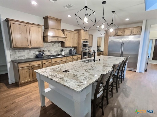 kitchen featuring decorative light fixtures, decorative backsplash, appliances with stainless steel finishes, a large island, and custom range hood