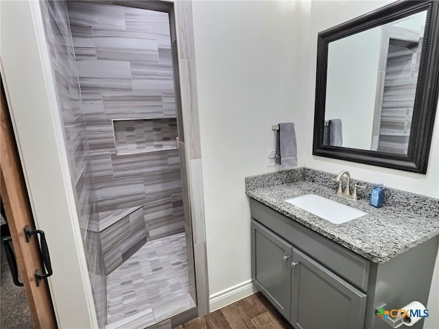 bathroom with tiled shower, hardwood / wood-style floors, and vanity