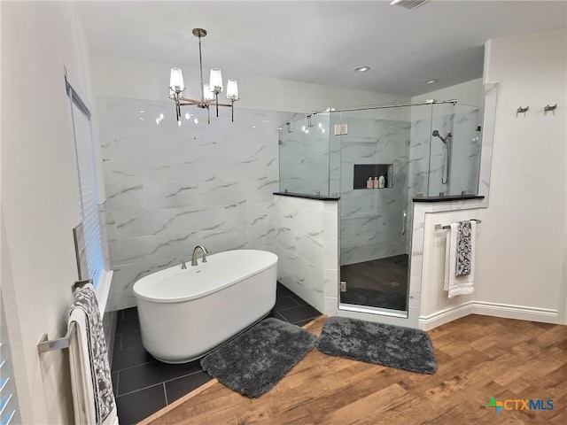 bathroom with hardwood / wood-style floors, shower with separate bathtub, and a chandelier