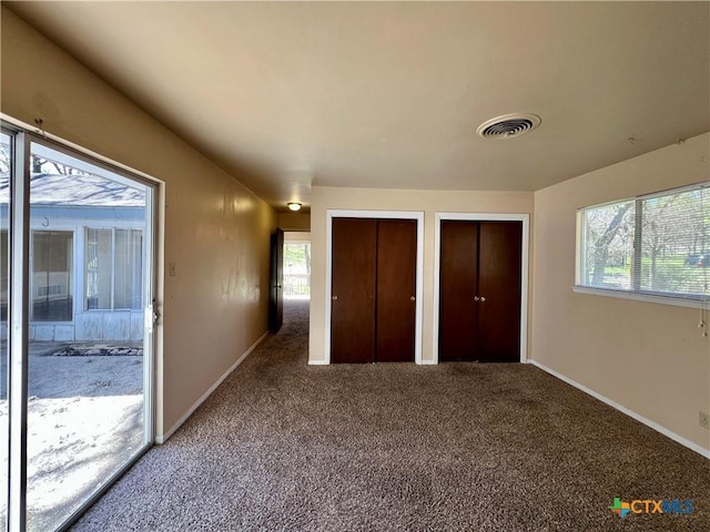 unfurnished bedroom with visible vents, multiple closets, carpet, and baseboards