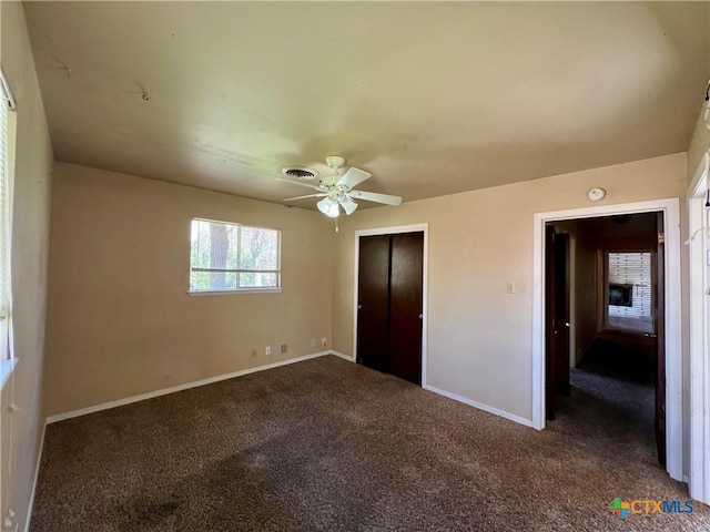 unfurnished bedroom featuring a ceiling fan, visible vents, carpet, baseboards, and a closet