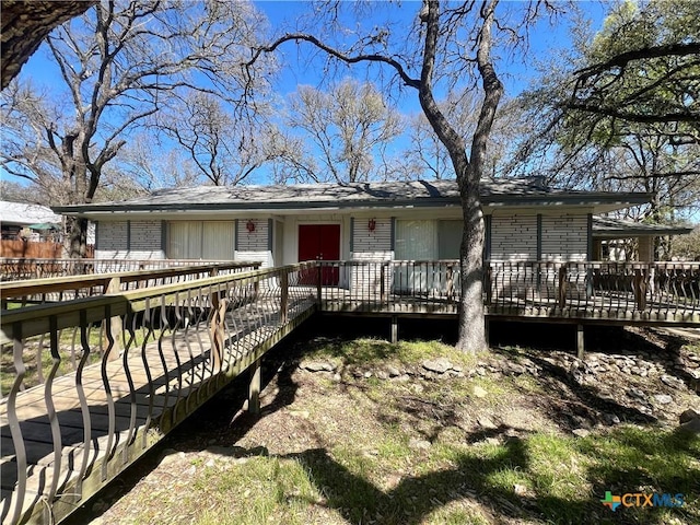 view of front facade with brick siding and a wooden deck