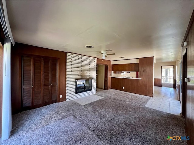 unfurnished living room with light tile patterned floors, visible vents, ceiling fan, light carpet, and a brick fireplace