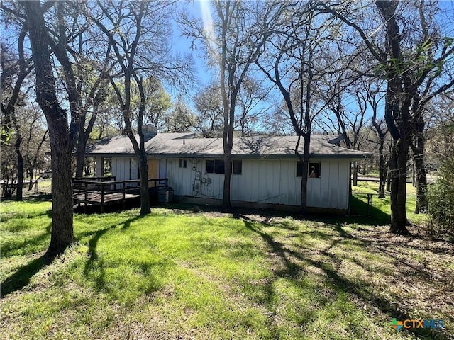 rear view of house featuring a lawn, board and batten siding, and a deck