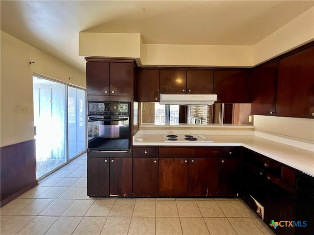 kitchen featuring light tile patterned floors, oven, light countertops, under cabinet range hood, and white electric cooktop