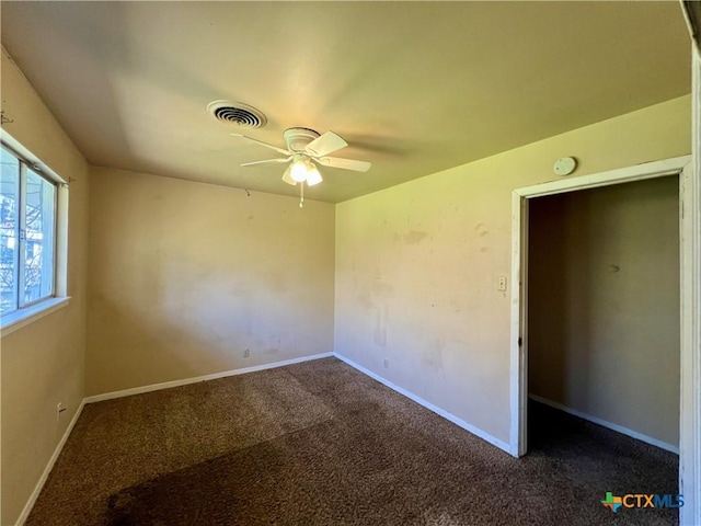 unfurnished room featuring visible vents, ceiling fan, baseboards, and dark colored carpet