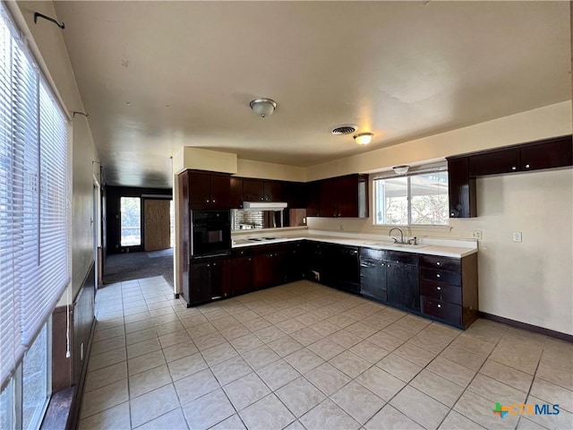 kitchen with visible vents, oven, light countertops, light tile patterned floors, and a sink