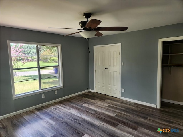 325 Montgomery St, Yoakum, TX 77995 - unfurnished bedroom featuring multiple windows, two closets, dark wood finished floors, and a ceiling fan