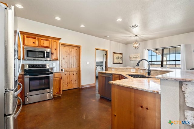 kitchen featuring appliances with stainless steel finishes, tasteful backsplash, light stone counters, sink, and hanging light fixtures