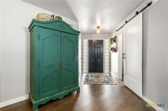 foyer with dark wood-type flooring and a barn door