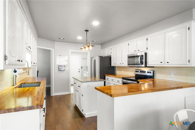 kitchen featuring white cabinetry, stainless steel appliances, kitchen peninsula, and butcher block countertops