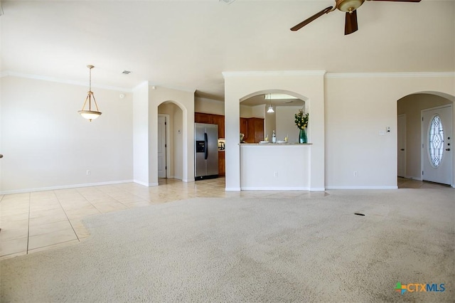 unfurnished living room with arched walkways, ceiling fan, baseboards, and ornamental molding