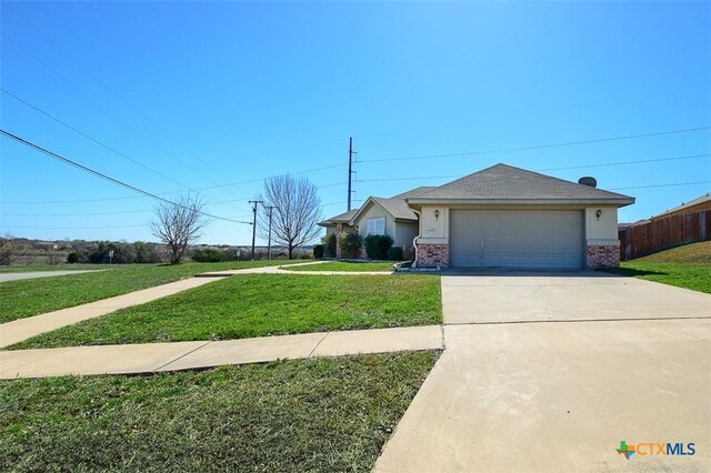 view of front of property featuring brick siding, fence, a front yard, a garage, and driveway