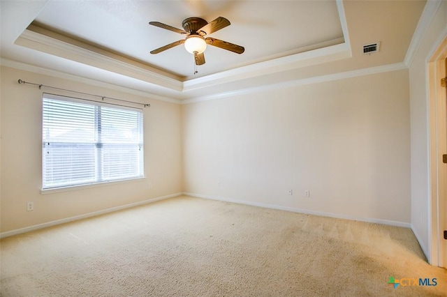 spare room with a tray ceiling, visible vents, and carpet flooring