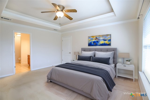 bedroom with visible vents, crown molding, baseboards, a tray ceiling, and ensuite bathroom