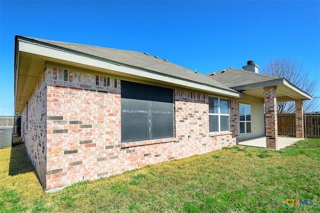 back of property featuring a yard, brick siding, a patio area, and fence