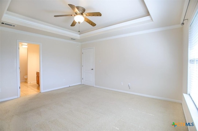 unfurnished bedroom featuring baseboards, visible vents, a tray ceiling, ornamental molding, and light carpet