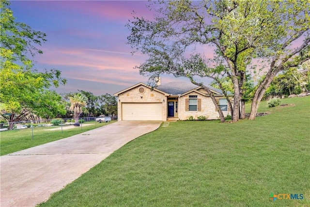 view of front of property with a yard, concrete driveway, an attached garage, fence, and stone siding