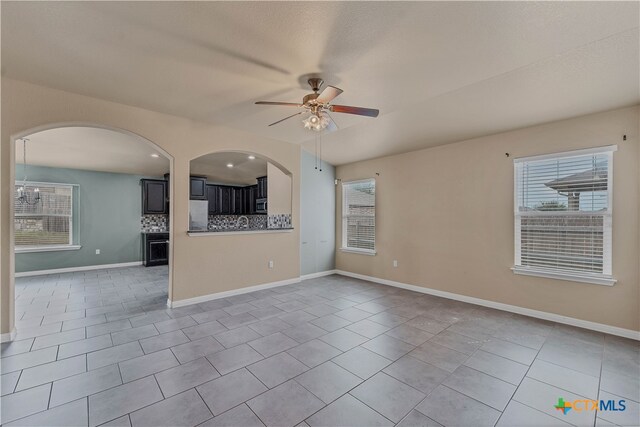 unfurnished living room featuring ceiling fan, plenty of natural light, and tile patterned flooring