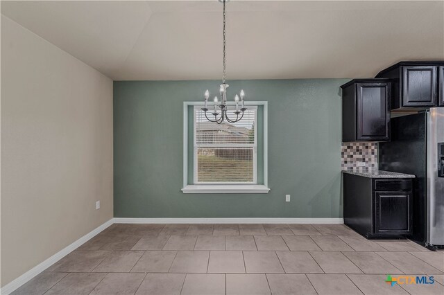 unfurnished dining area with light tile patterned flooring and a notable chandelier