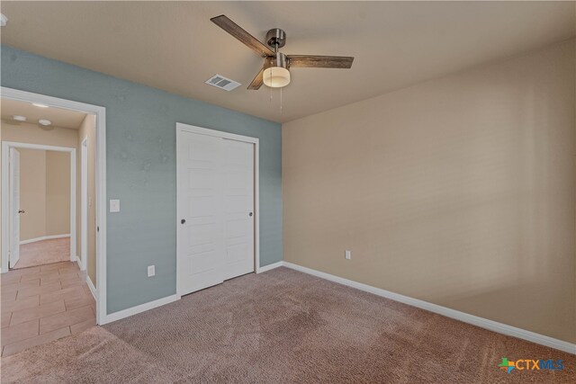 unfurnished bedroom featuring light carpet, ceiling fan, and a closet