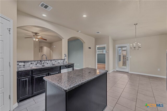 kitchen with sink, light stone counters, decorative light fixtures, a center island, and dishwasher