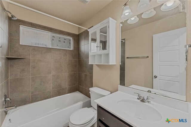 full bathroom featuring tiled shower / bath combo, vanity, and toilet