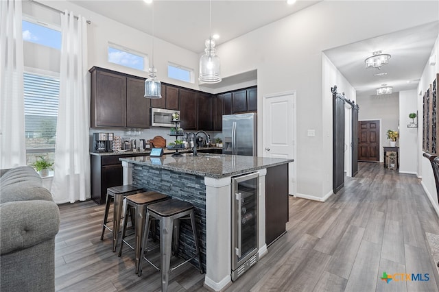 804 Blue Oak Blvd, San Marcos, TX 78666 - kitchen with stainless steel appliances, beverage cooler, a barn door, a breakfast bar, and dark stone counters