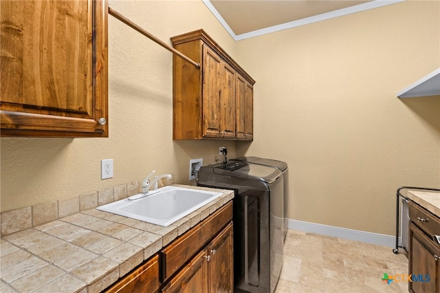 laundry area featuring cabinets, washing machine and dryer, sink, and crown molding