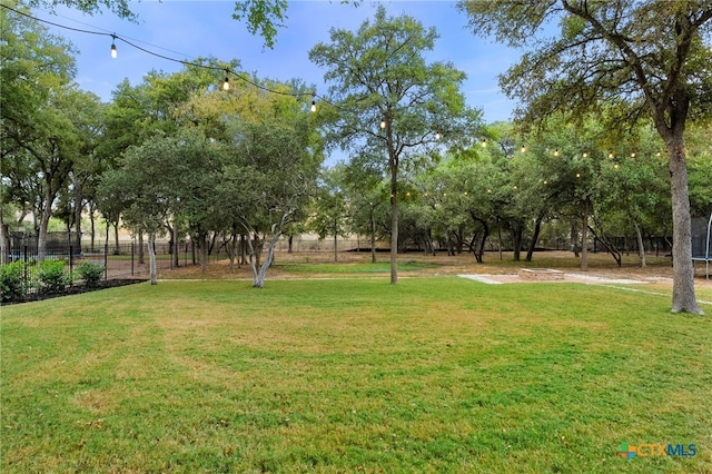 view of yard with a fire pit, a trampoline, and fence
