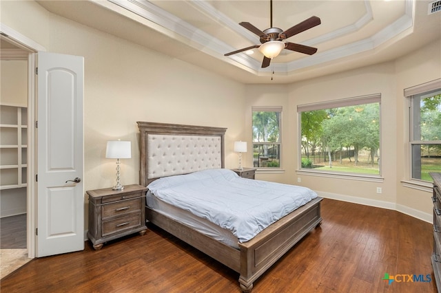 bedroom featuring dark wood-type flooring, a tray ceiling, ceiling fan, and crown molding