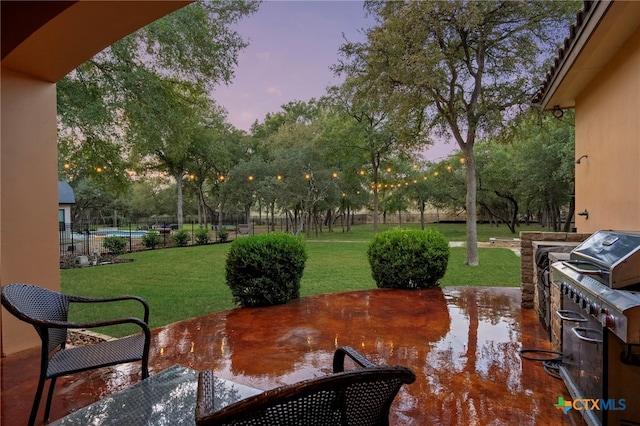 patio terrace at dusk featuring a swimming pool, a lawn, and a grill