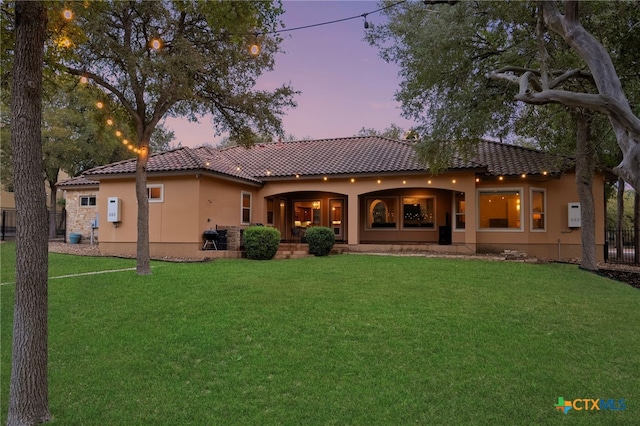 back house at dusk featuring a yard