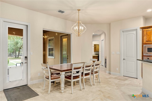 dining space featuring baseboards, visible vents, arched walkways, and an inviting chandelier