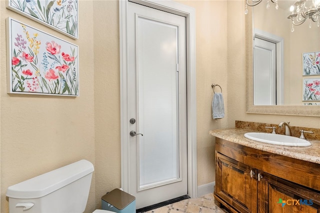 bathroom with vanity, toilet, and a notable chandelier