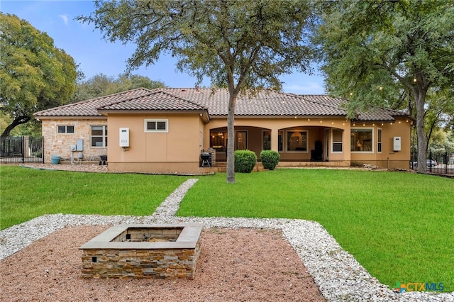 rear view of house with a lawn and an outdoor fire pit